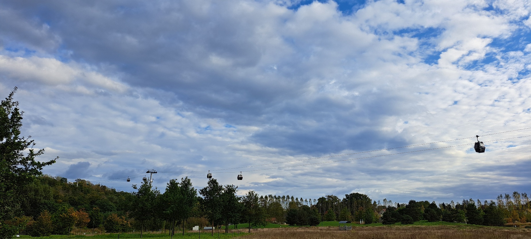 weißblauer Wolkenhimmel, Seilbahngondeln