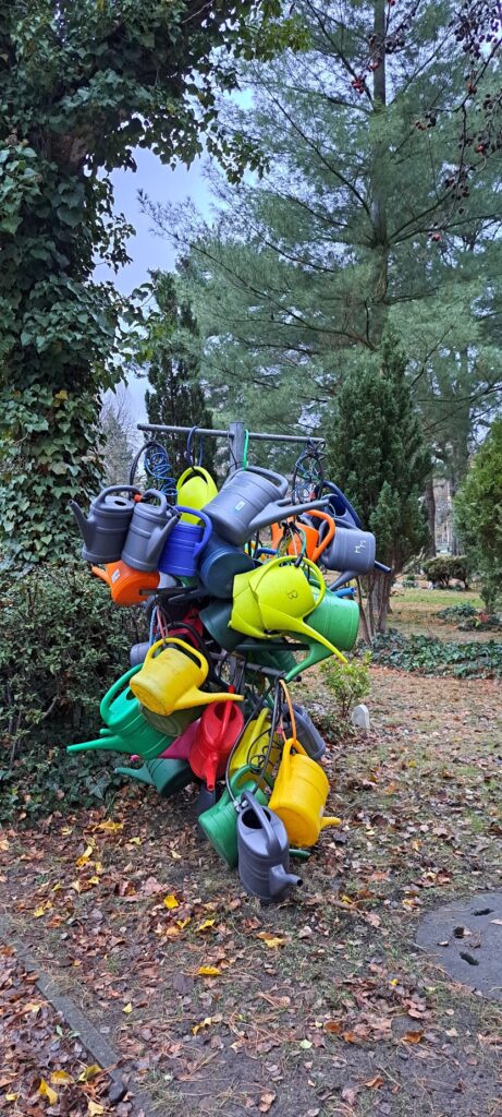 beschriftete und mit Fahrradschlössern angeschlossene Gießkannen