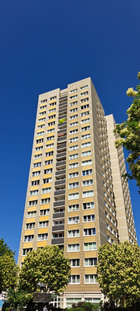Hochhaus vor blauem Himmel und blühenden Bäumen