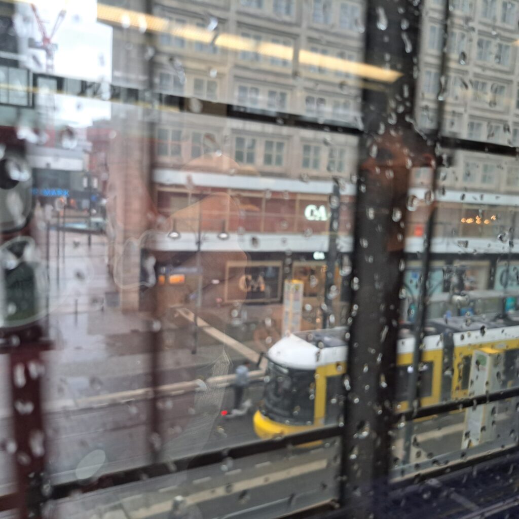 Regentropfen auf einer Scheibe, verschwommen eine Straßenbahn im Hintergrund