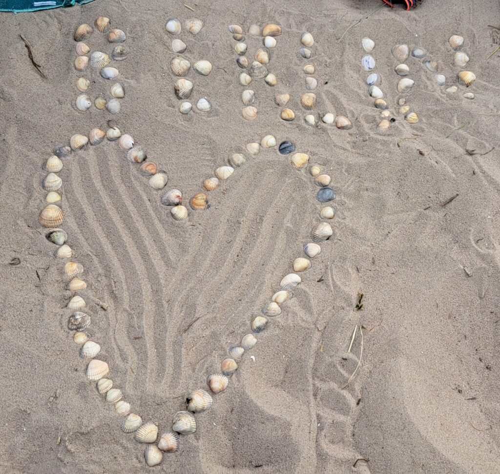Im Sand wurde ein Herz au Herzmuscheln gelegt und das Wort Berlin