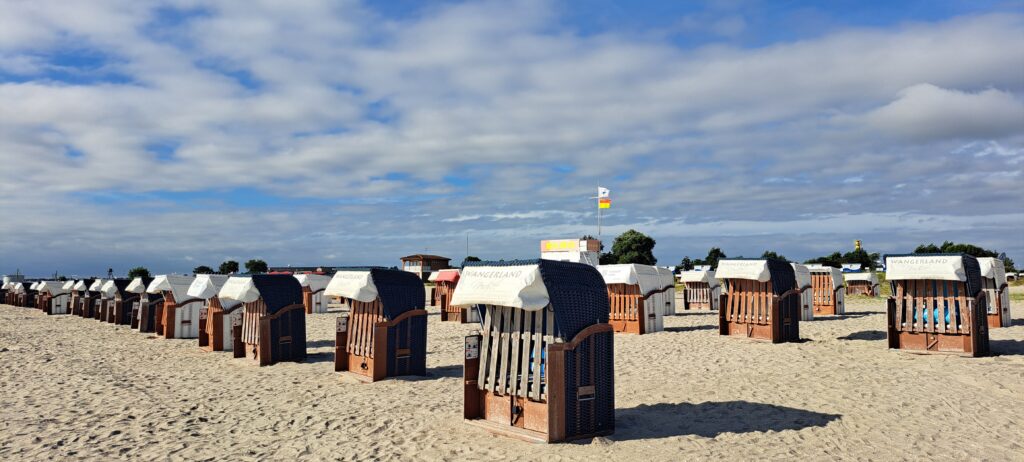 geschlossene Strandkörbe vor blauweißem Himmel am Strand