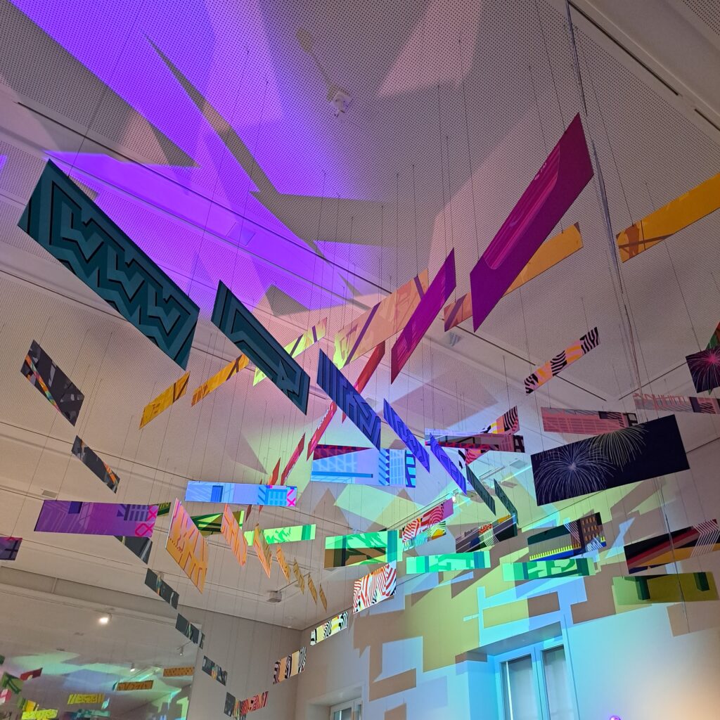 Deckenkunstwerk, aus bunten linienförmig aufgehängten Streifen