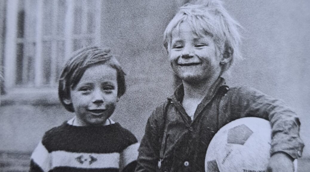 schwarzweiß Postkarte mit zwei Kidnern, einer trägt einen Fußball unterm Arm